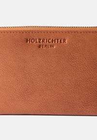 Leather wallet in warm brown with a textured finish, featuring embossed "HOLZRICHTER BERLIN" branding and a gold zipper closure.
