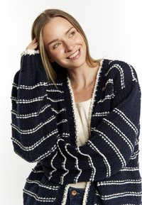 Cardigan lavorato a maglia blu navy con strisce bianche e finitura testurizzata. Design con apertura frontale, maniche larghe e bordo crema lungo i lati.