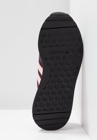 Adidas sneakersula med ett svart gummihexagonmönster och ränder i mörklila och ljusrosa på sidan.