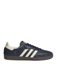 Sneaker Adidas Samba blu navy con strisce bianche, linguetta beige sul tallone, suola nera e testo dorato "SAMBA" sul lato.