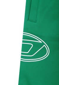 Groene sportshorts van zachte stof, met een opvallend wit logo en stikseldetails. Bevat een klein zakje aan de zijkant.