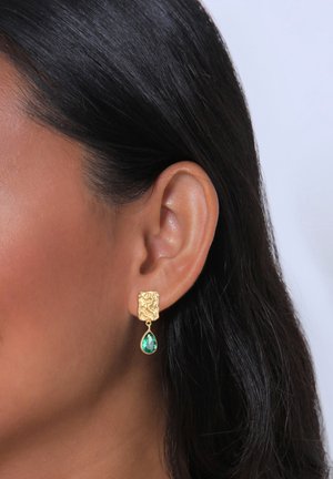 Goldene Ohrringe mit einem strukturierten quadratischen Stecker und einem grünen Tropfen-Cabochon-Anhänger, der komplexe Details und eine polierte Oberfläche aufweist.