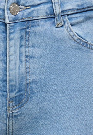 Ljusblå jeans i denim som visar framficka, bältesögla och metallknapp med synliga sömmar.