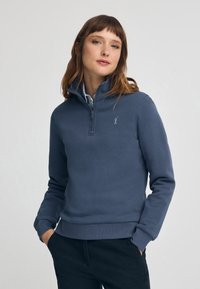 Mörkblå zip-up fleece-tröja med hög krage, med en diskret logotyp på bröstet och ribbade muddar och fåll.
