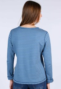 Blaue gestreifte Langarmbluse mit rundem Halsausschnitt, strukturierten Saumdetails und entspannter Passform. Das Material wirkt weich und elastisch.