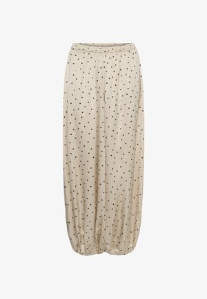 Beige losse broek met zwarte polka dots, elastische tailleband en elastische boorden bij de enkels die zijn gerimpeld.