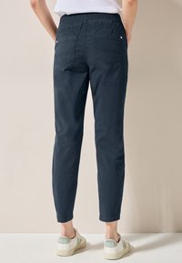 Pantalons légers bleu marine avec une taille élastique, deux poches arrière et une coupe fuselée, présentant un poignet au niveau de la cheville.