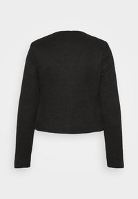 Veste courte noire texturée à manches longues avec un col rond, vue de dos sur un fond clair uni.