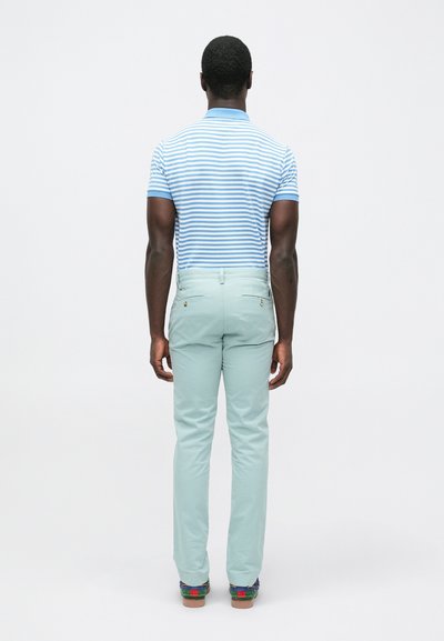 Ριγέ polo πουκάμισο σε μπλε και λευκό με γιακά, συνδυασμένο με παντελόνι σε μέντα πράσινο. Προβολή από πίσω, δείχνοντας τη εφαρμογή και τα χρώματα.