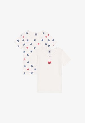 Deux chemises à manches courtes en coton doux ; l'une blanche avec des motifs de cœurs rayés rouges et bleus, l'autre blanche simple avec un cœur rayé rouge.