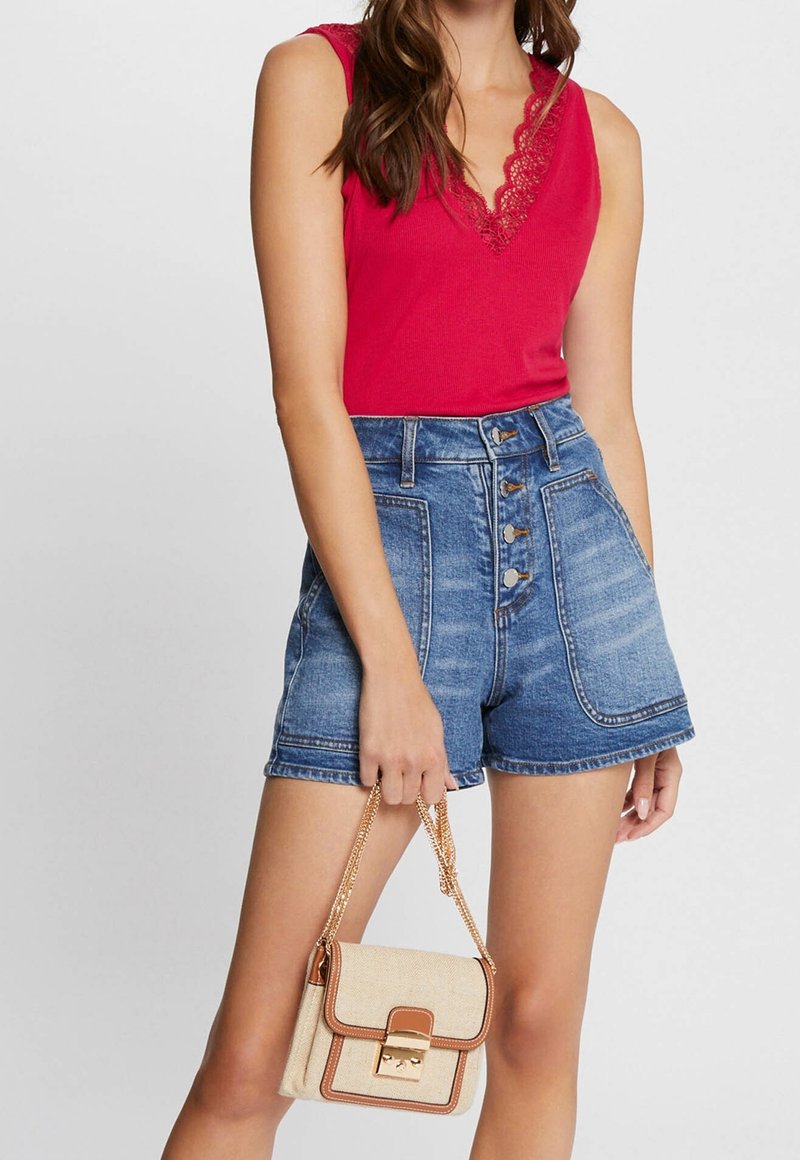 Rød ærmeløs top med blonder, højtaljede denim shorts med knaplukning, og en cremefarvet crossbody-taske med guld kædested.