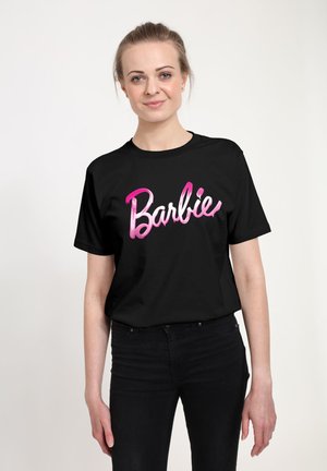 Černé tričko s růžovou a bílou grafikou "Barbie" v kurzívě. Design kontrastuje s látkou a vytváří vizuální zájem.