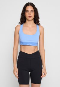 Hellblauer Sport-BH mit quadratischem Ausschnitt und Calvin Klein Logo-Band, kombiniert mit hoch taillierten schwarzen Radlerhosen.