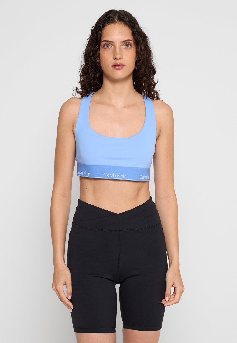 Hellblauer Sport-BH mit quadratischem Ausschnitt und Calvin Klein Logo-Band, kombiniert mit hoch taillierten schwarzen Radlerhosen.