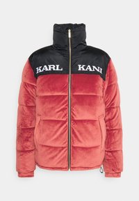 Červená a černá bunda s nadýchanou výplní, vysokým límcem, zlatým zipem, měkkou strukturou, velkými předními kapsami a logem "KARL KANI" na hrudi.