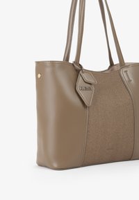 Borsa a tote in finta pelle marrone con pannello in tela, due manici e etichetta removibile. Presenta finiture in oro e una forma strutturata.