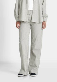 Gestreepte lichtgroene en witte lange mouwen shirt gecombineerd met bijpassende wijde broek, vervaardigd uit een gestructureerde stof en met een ontspannen pasvorm.