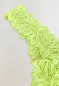 Dentelle en vert lime éclatant, présentant un motif floral avec des bords festonnés et des détails fins, mettant en avant une texture délicate.
