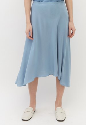 Jupe midi en satin bleu clair avec un ourlet asymétrique, texture lisse et design fluide. Associée à des mocassins blancs à enfiler.