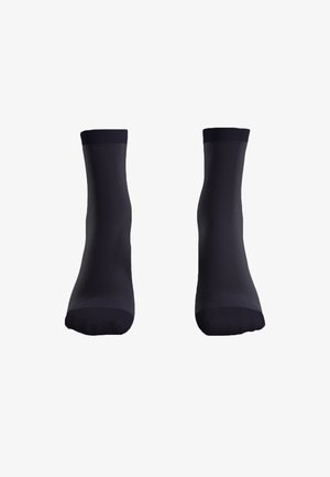 Calzini neri con una texture liscia, caratterizzati da un polsino a costine, lunghezza a metà polpaccio e un design semplice e senza cuciture.