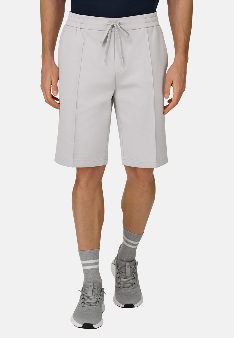 Hellgraue Sportshorts aus weichem Stoff, mit einem elastischen Bund mit Kordelzug und seitlichen Taschen. Kombiniert mit grauen Turnschuhen und Socken.