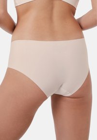 Lys beige sømløs hipster-undertøy med en glatt tekstur og minimalistisk design, med en bred, flat midje.
