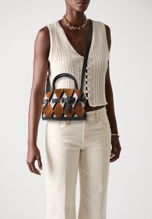 Small handbag featuring a geometric pattern in brown, black, and white with a leather handle and strap, displaying a bow accent and logo detail.