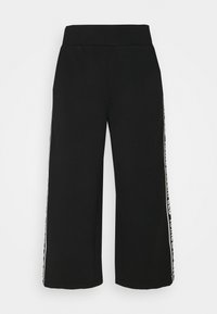 Czarne spodnie z szerokimi nogawkami, wykonane z miękkiego materiału, z wysokim stanem. Posiadają kontrastowe białe paski po bokach z wzorem tekstowym wzdłuż szwów.