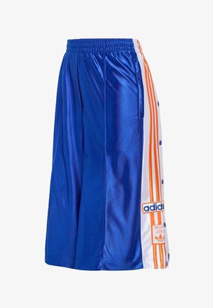Pantalones deportivos de satén azul con paneles laterales blancos, rayas naranjas, botones automáticos y parches con el logo de Adidas en la pierna derecha.