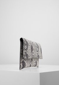 Pochette en simili serpent gris et noir, fabriquée dans un matériau texturé, dotée d'une fermeture rabat et d'un accent métallique à l'avant.