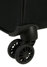 Angolo di una valigia nera con tessuto testurizzato, alloggiamento robusto per le ruote in plastica e due ruote girevoli durevoli con motivi geometrici.