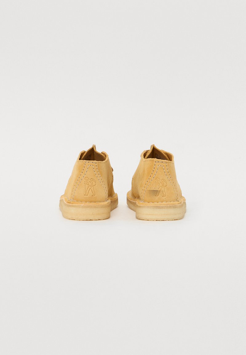 Gele leren schoenen met een zachte suède afwerking, afgeronde achterkant en reliëf logo detail. Voorzien van zichtbare stiksels en een flexibele rubberen zool.