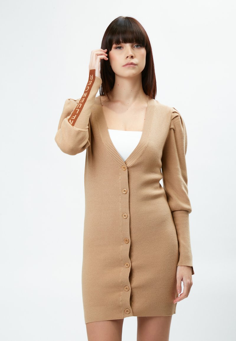 Khaki gebreide cardigan met lange, puffende mouwen, een V-halslijn en sluiting met knopen aan de voorkant; heeft logo-detail op de mouw.