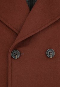 Brązowy wełniany płaszcz z dużym kołnierzem, wyposażony w dwie ciemne guziki i miękką, teksturowaną powierzchnię. Widoczna zamykana podszewka.