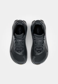 Zwarte trailrunning schoenen met een gestructureerde bovenkant, stevige zool en reflecterende accenten. Voorzien van veters en demping voor comfort.