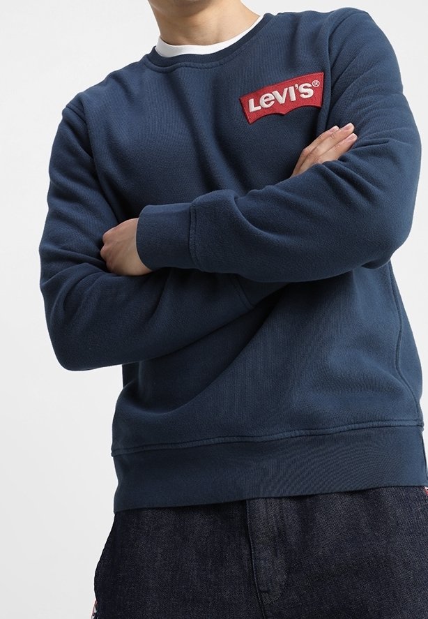 Námořnický modrý svetr s kulatým výstřihem z texturované látky, s červeným logem Levi's na hrudi a žebrovanými manžetami a lemem.