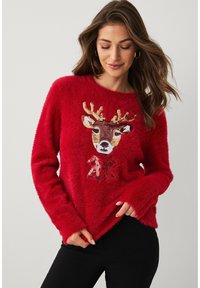 Rode, zachte trui met een rendierontwerp met pailletten in bruin, wit en goud. Ronde hals en lange mouwen met brede manchetten.