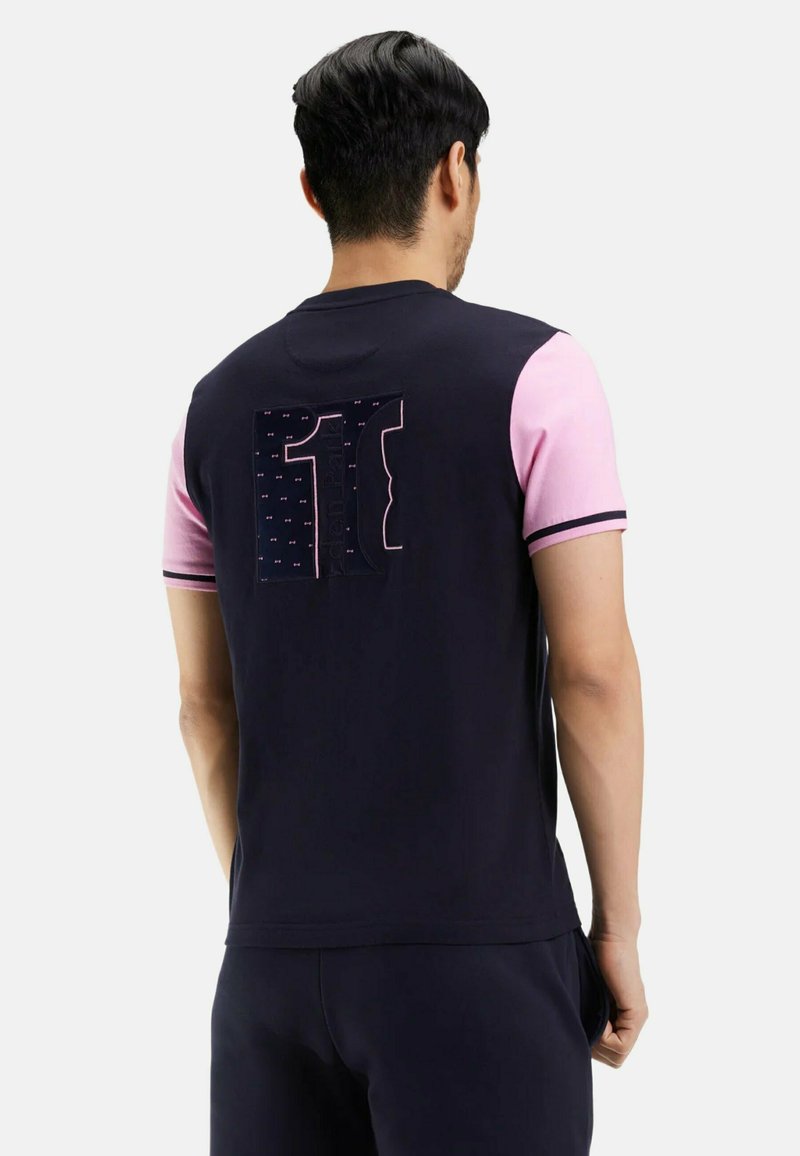 T-shirt à manches courtes bleu marine et rose avec un graphique « 11 » en grand au dos, présentant des textures de tissu contrastantes et une coupe slim.