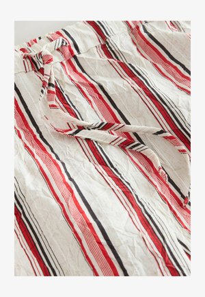 Stribet stof med røde, sorte og hvide linjer. Blødt, tekstureret materiale med en indsnævret talje og bundet detalje.