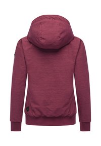 Bordeaux jakke med stor hette, strukturert stoff, elastiske mansjetter og en tætsittende underkant. Har en logopatch på venstre erme.