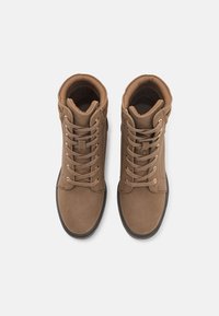 Bottines en cuir marron, à bout arrondi, avec un design à lacets, un col rembourré et une surface texturée ; dotées d'œillets dorés et d'une semelle noire.