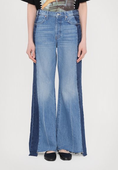 Jean large bleu clair avec des panneaux latéraux contrastants de bleu foncé, des ourlets effilochés et un design classique à cinq poches.