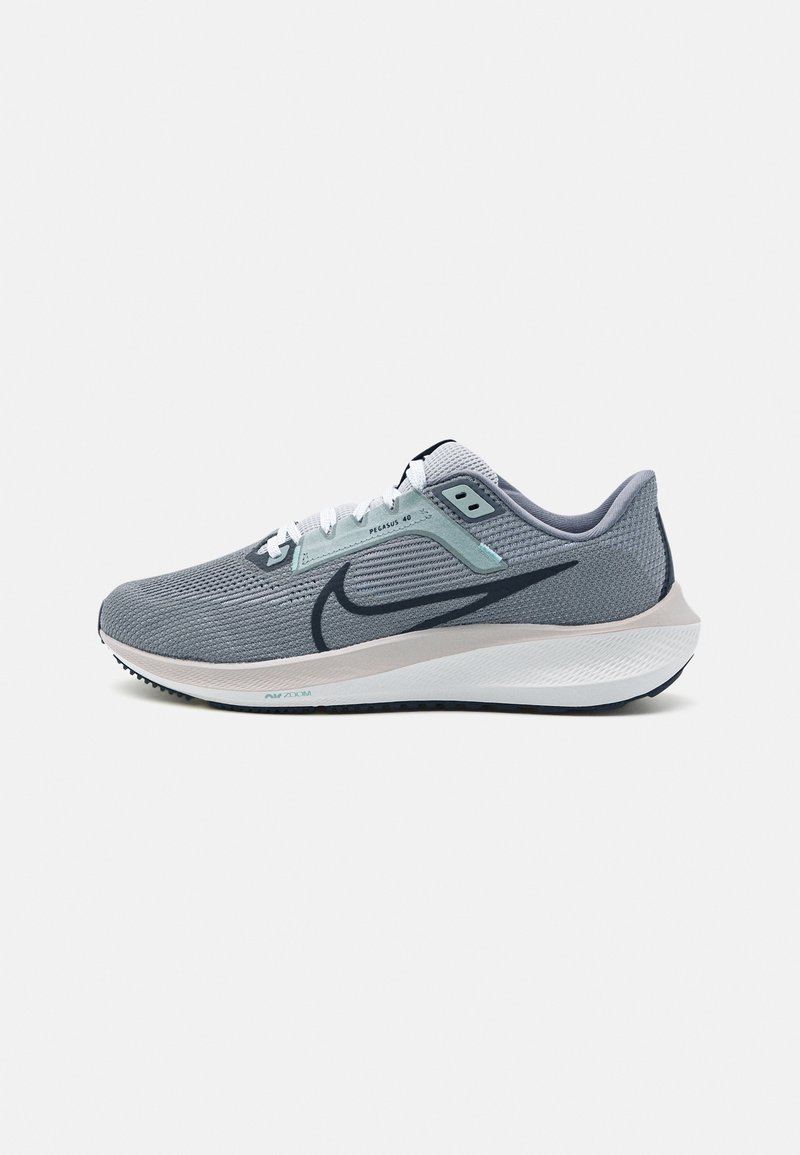 Le scarpe da corsa Nike Pegasus 40 presentano una tomaia in mesh grigia, lacci bianchi e un design elegante. La suola è di un grigio chiaro con un motivo testurizzato.