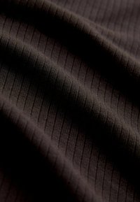 Tumepruun ripsitud kangas peente vertikaalsete joontega, pehme tekstuur ja kerge sära. Materjal näib olevat veniv ja kerge.