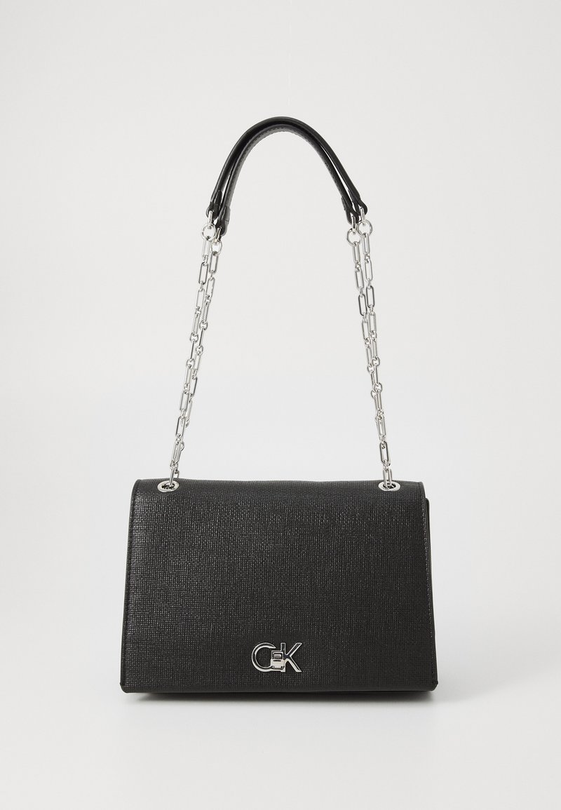 Black handbag with a textured finish, featuring a leather top handle and silver chain strap. Notable logo displayed on the front.