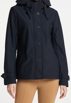 Marineblaue Kapuzenjacke mit vorderer Knopfverschluß, verstellbaren Bündchen und Seitentaschen, getragen über beigefarbenen, eng anliegenden Hosen.