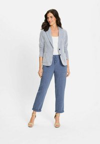 Gestreepte blazer in lichtblauw en wit met twee voorzakken, gecombineerd met marineblauwe broek met trekkoord. G gedragen met tan enkelband hakken.