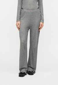 Γκρι πλεκτό παντελόνι με φαρδιά παντελόνα και λείο ζωνάρι στη μέση, με απαλή υφή και διακριτικό ριμπ, σε συνδυασμό με μαύρα παπούτσια με υφή.