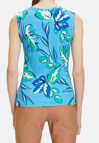 Top sin mangas de tela azul claro con un gran patrón floral en verde y azul. Presenta un escote redondo y un diseño ajustado.