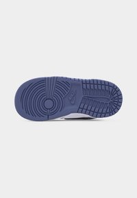 Πάτος ενός μπλε και άσπρου αθλητικού παπουτσιού Nike που παρουσιάζει κυκλικά σχέδια λαβής και ορθογώνια πέλματα με το λογότυπο Nike χαραγμένο στο κέντρο.